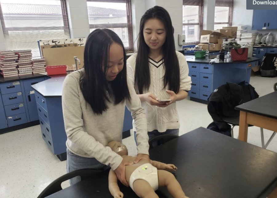 Founder, Emily Chan and Sophia Cheng practicing CPR on a baby dummy 